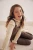 next-bezowy-sweter-golf-z-falbanka-prazkowany-modelka-siedzaca2.webp