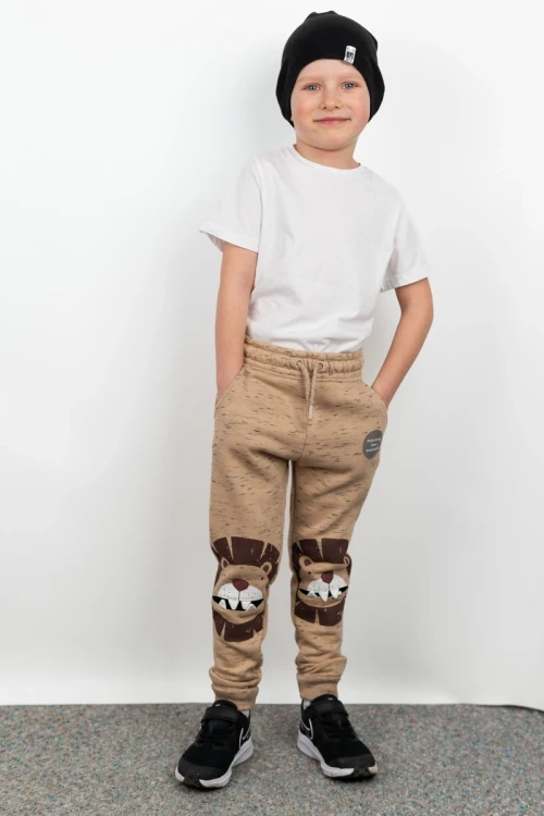 Nutmeg-dzieciece-spodnie-dresowe-bezowe-lew-model-przod2.webp