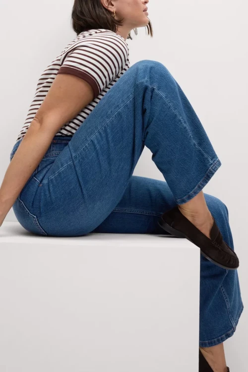 M&S-ciemne-jeansowe-spodnie-szeroka-nogawka-jeans-modelka-siedzaca.webp