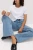 M&S-jasne-jeansowe-spodnie-szeroka-nogawka-jeans-modelka-siedzaca.webp