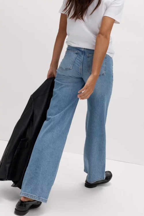 M&S-jasne-jeansowe-spodnie-szeroka-nogawka-jeans-modelka-tyl.webp