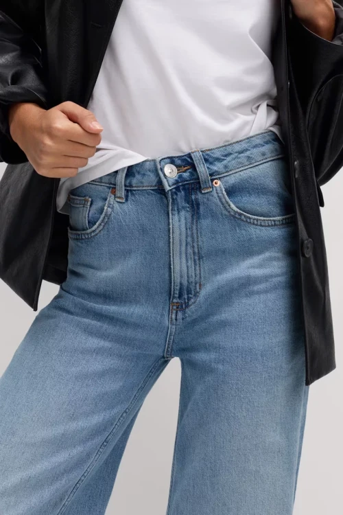 M&S-jasne-jeansowe-spodnie-szeroka-nogawka-jeans-modelka-zblizenie.webp
