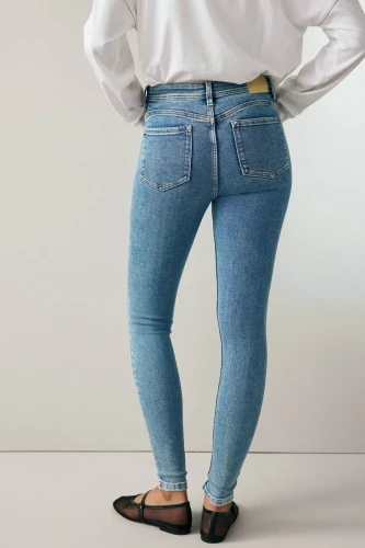 Next-jasne-jeansowe-melanzowe-damskie-jeansy-modelka-tyl.webp